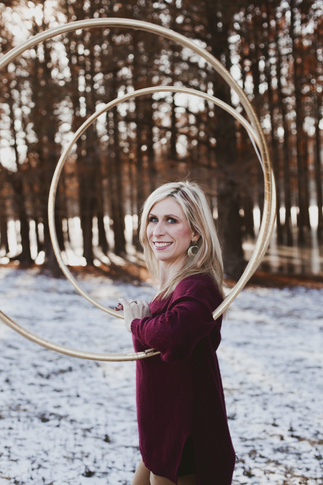 Michele McCoy smiling with two gold hoops in a snowy woodland