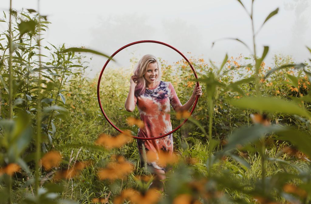 Katie Sunshine smiling with a red hula hoop