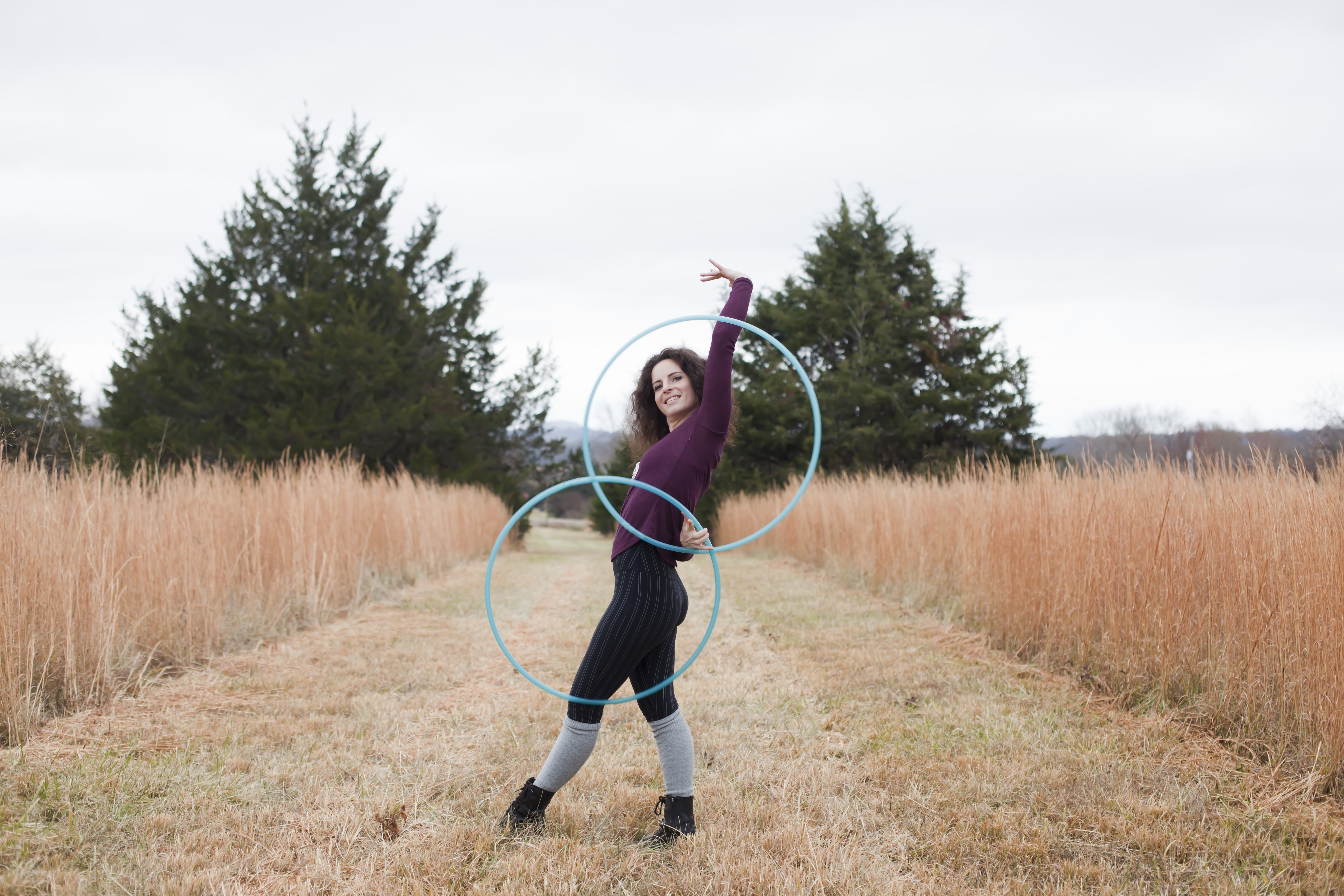 Caterina Suttin Holdbrook hoop dancing outdoors with three teal hoops.