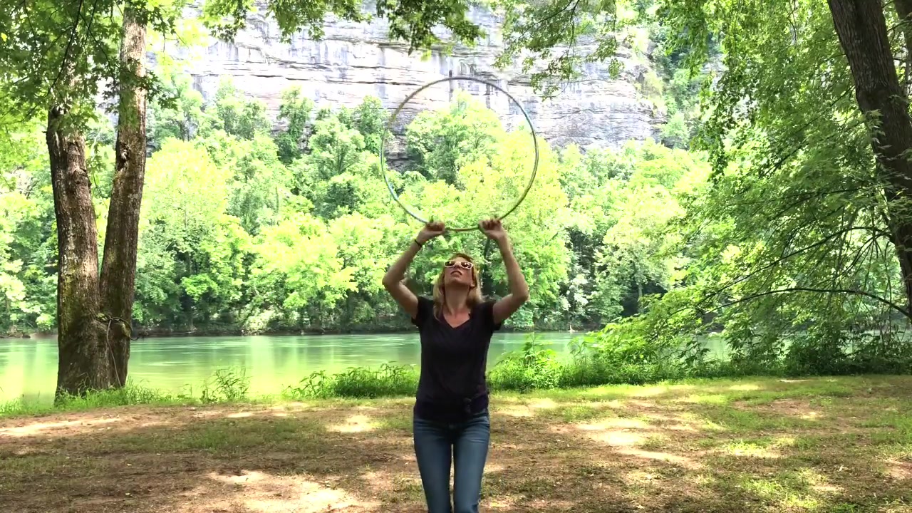Michele McCoy catching a yellow hoop above her head during a chest roll pop demonstration outdoors.