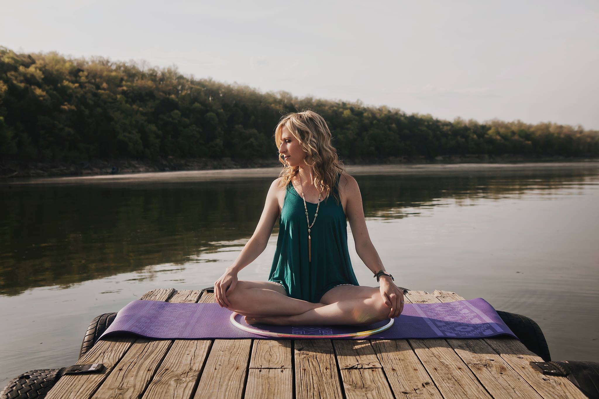 Michele McCoy meditating beside a lake with a hoop