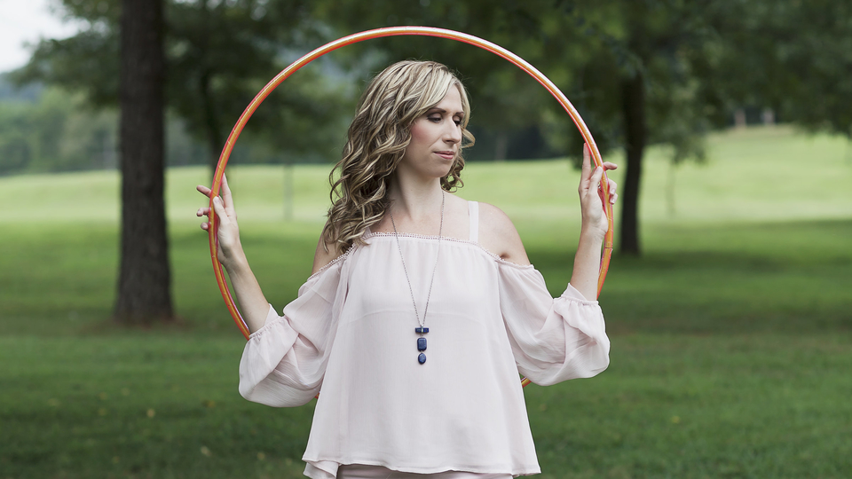 Michele McCoy holding an orange hoop outdoors.