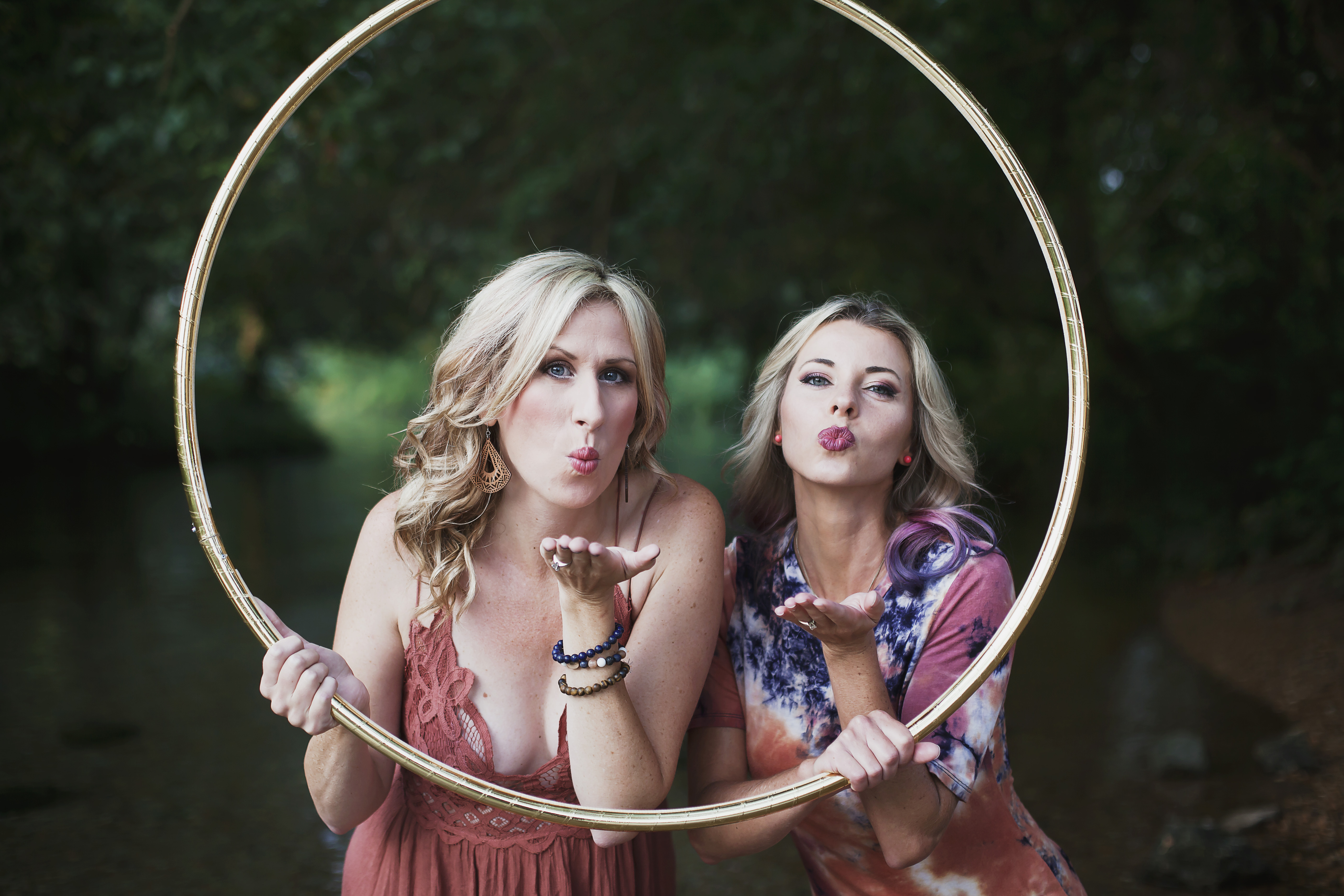Michele McCoy and Katie Sunshine smiling together inside a gold hula hoop
