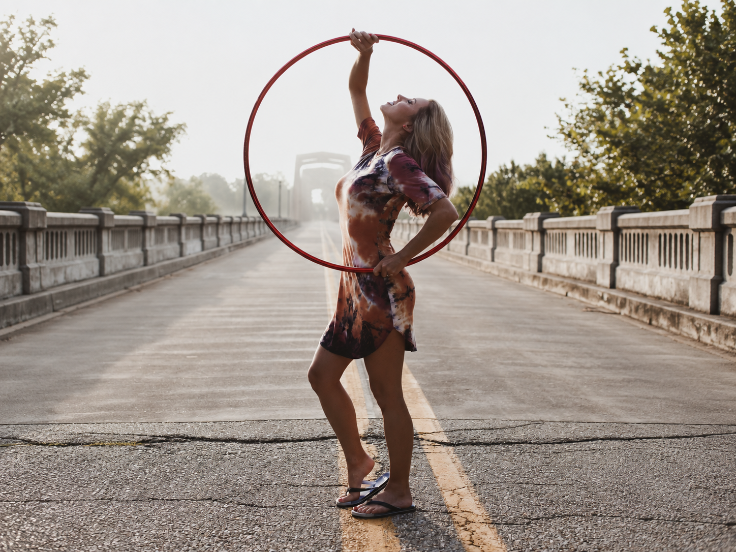 Katie Sunshine posing inside a red hoop on a wooden bridge